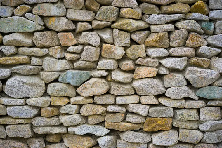 Mur de moellons arrondis aux tons gris, ocre et rouille