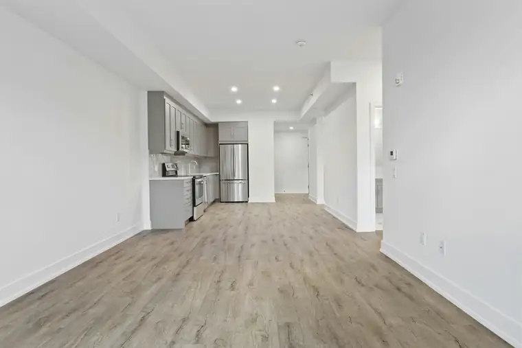 Pièce vide refaite à neuf : parquet clair, murs blancs, spots au plafond